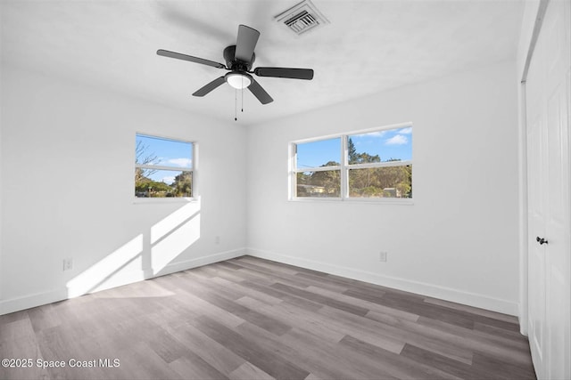 empty room featuring ceiling fan, a healthy amount of sunlight, and hardwood / wood-style floors