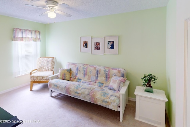 sitting room featuring ceiling fan, light carpet, and a textured ceiling