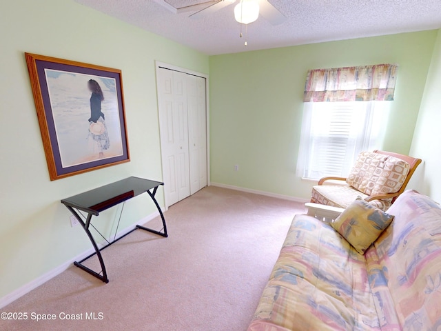 living area with ceiling fan, light colored carpet, and a textured ceiling