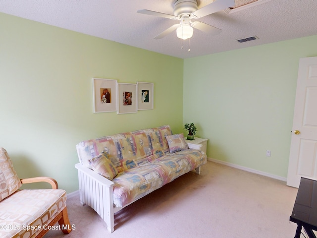 living room featuring ceiling fan, light colored carpet, and a textured ceiling