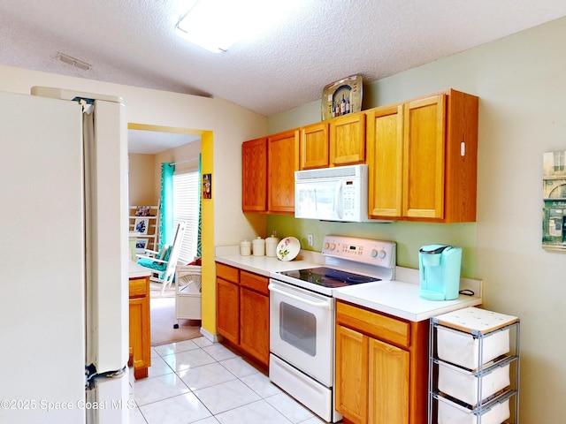 kitchen with white appliances, a textured ceiling, and light tile patterned floors