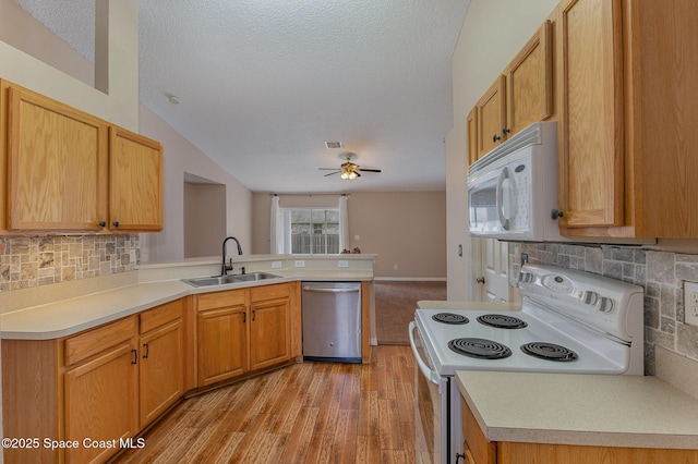 kitchen featuring a textured ceiling, white appliances, tasteful backsplash, sink, and kitchen peninsula