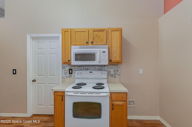 kitchen featuring light wood-type flooring, decorative backsplash, and white appliances