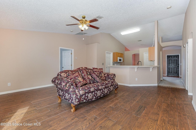 living room with ceiling fan, a textured ceiling, dark hardwood / wood-style flooring, and vaulted ceiling