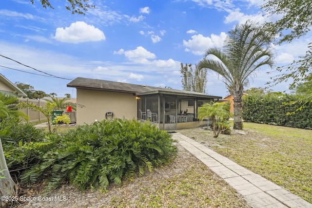 back of property featuring a yard and a sunroom