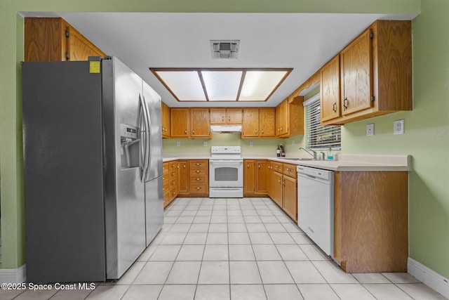 kitchen with light tile patterned floors, a skylight, sink, and white appliances