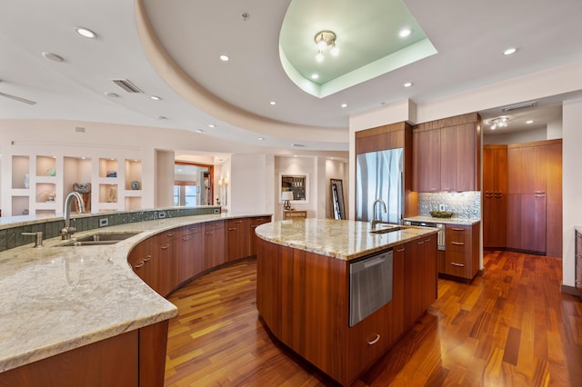 kitchen featuring built in refrigerator, light stone countertops, dark hardwood / wood-style floors, a large island, and a tray ceiling