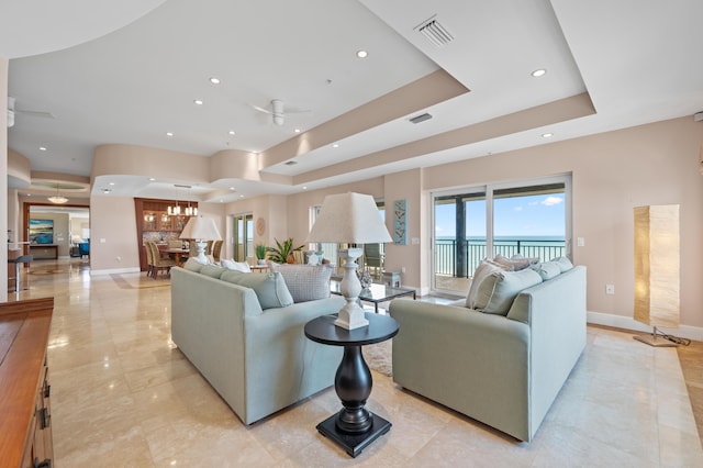 living room featuring ceiling fan and a tray ceiling