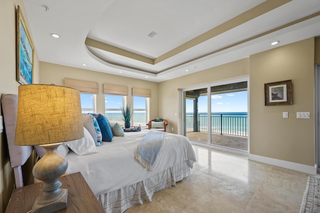 bedroom with access to exterior, a water view, a tray ceiling, and multiple windows