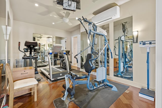 exercise room featuring ceiling fan, an AC wall unit, and wood-type flooring