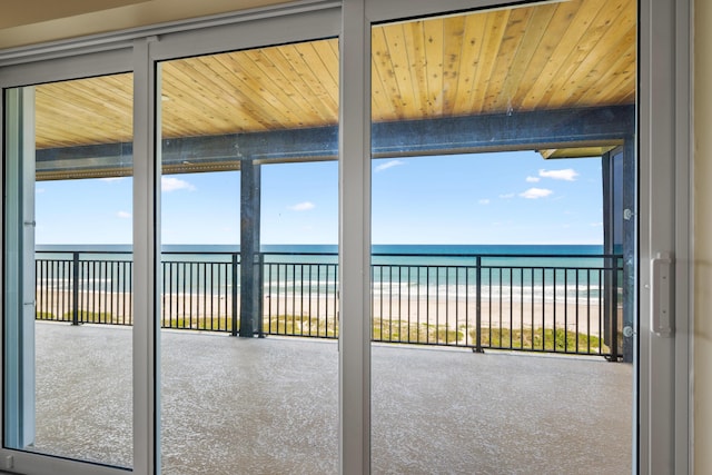 unfurnished sunroom with a water view, wood ceiling, and a beach view