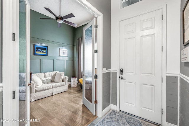 foyer with wood-type flooring, a textured ceiling, and ceiling fan