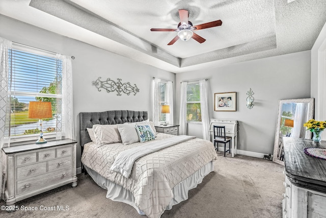 carpeted bedroom featuring a textured ceiling, a raised ceiling, and ceiling fan