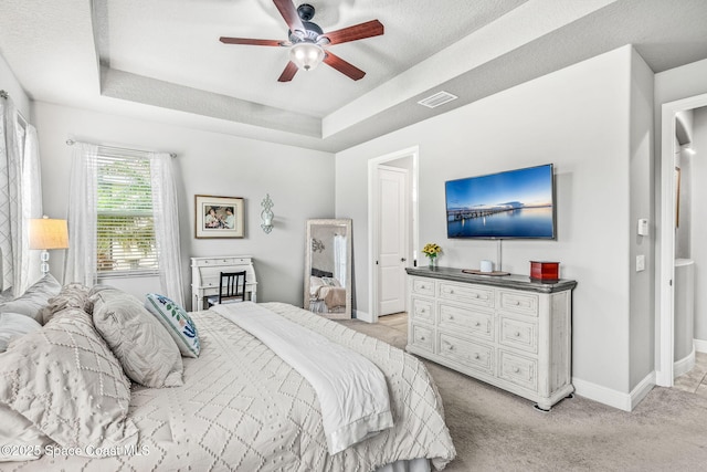 bedroom with ceiling fan, a raised ceiling, and light colored carpet