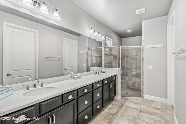 bathroom featuring vanity, a shower with shower door, and a textured ceiling