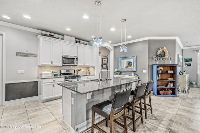 kitchen featuring white cabinetry, sink, stainless steel appliances, and an island with sink