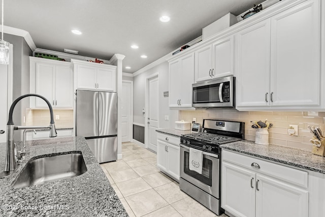 kitchen with appliances with stainless steel finishes, sink, white cabinets, light tile patterned floors, and crown molding