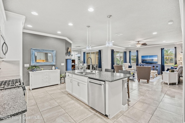 kitchen featuring sink, white cabinetry, stainless steel appliances, light stone countertops, and a center island with sink