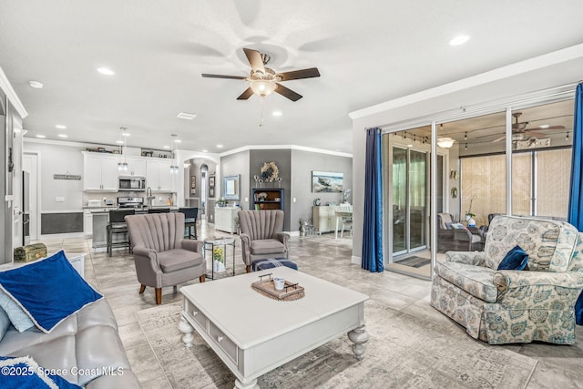 living room featuring light tile patterned floors, crown molding, and ceiling fan