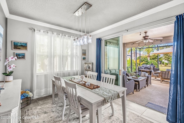 tiled dining area featuring ceiling fan, crown molding, and a textured ceiling