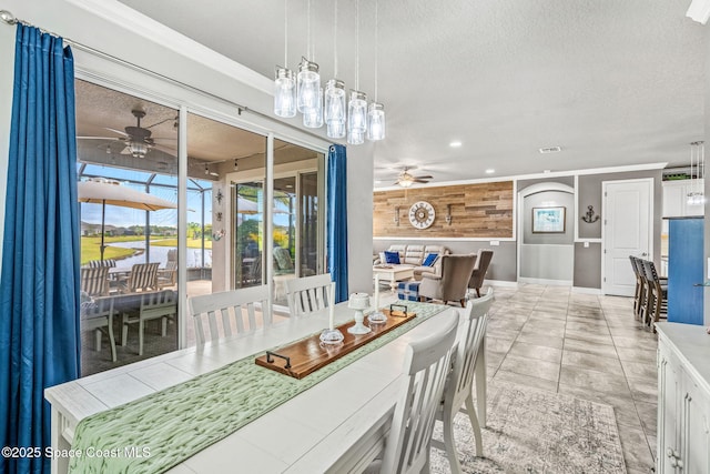 tiled dining room with ornamental molding, a textured ceiling, and ceiling fan