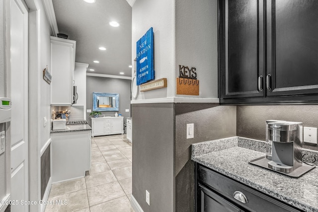 kitchen featuring crown molding, light tile patterned flooring, light stone countertops, and white cabinets