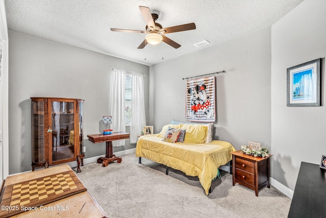 bedroom with ceiling fan, light colored carpet, and a textured ceiling