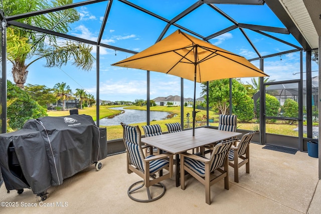 view of patio featuring a grill, glass enclosure, and a water view