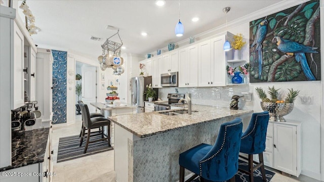 kitchen with white cabinets, kitchen peninsula, light stone countertops, and stainless steel appliances