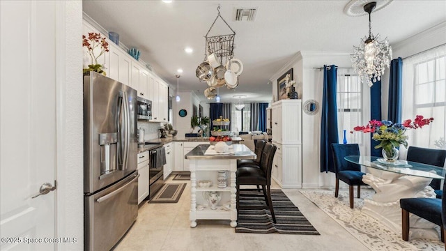 kitchen with white cabinetry, a center island, stainless steel appliances, and an inviting chandelier