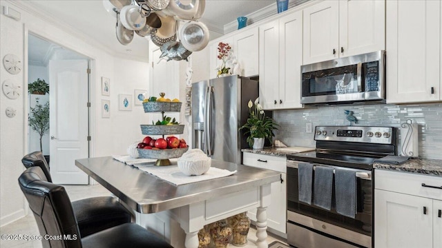 kitchen featuring decorative backsplash, ornamental molding, stainless steel appliances, and white cabinetry