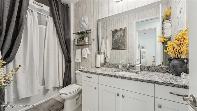 full bathroom with toilet, vanity, shower / bath combo, and wood walls