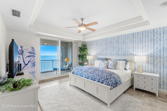 tiled bedroom featuring a tray ceiling, access to outside, and ceiling fan