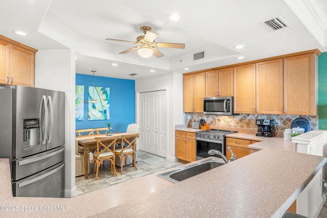 kitchen with appliances with stainless steel finishes, kitchen peninsula, sink, and decorative backsplash