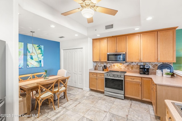 kitchen with tasteful backsplash, stainless steel appliances, decorative light fixtures, and a tray ceiling