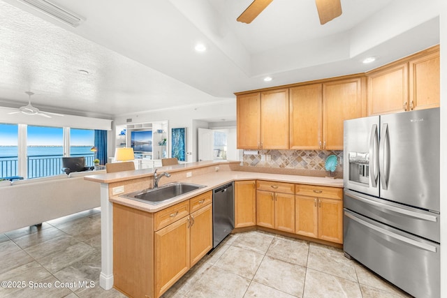 kitchen featuring sink, kitchen peninsula, ceiling fan, stainless steel appliances, and decorative backsplash