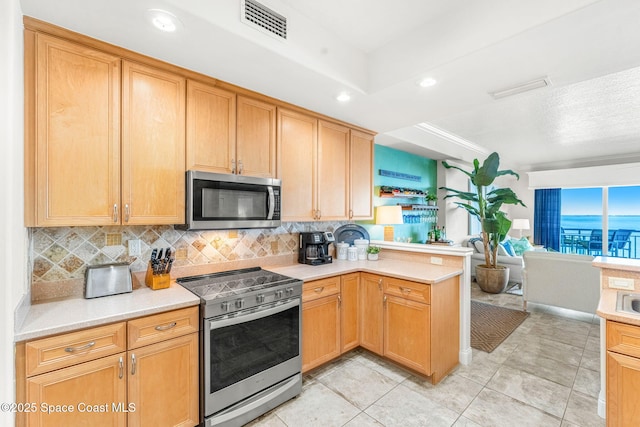 kitchen featuring backsplash, light tile patterned flooring, kitchen peninsula, and appliances with stainless steel finishes