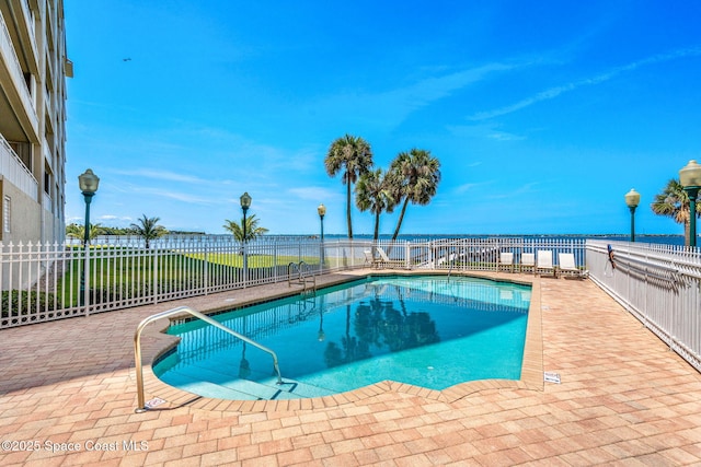 view of pool with a patio and a water view