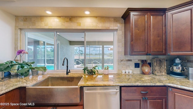 kitchen with light stone countertops, sink, backsplash, and dishwasher