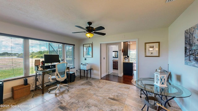 home office featuring ceiling fan and a textured ceiling