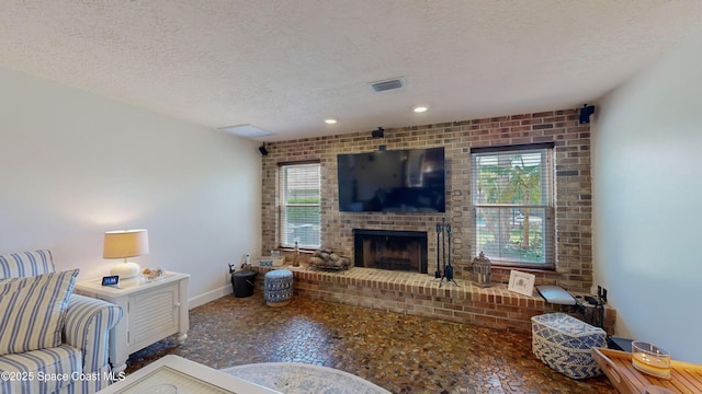 living room with brick wall, a fireplace, plenty of natural light, and a textured ceiling