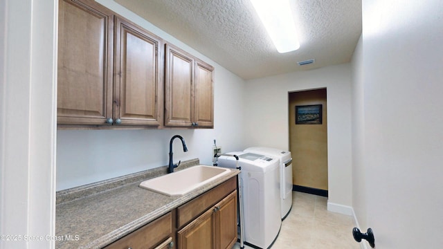 clothes washing area featuring sink, separate washer and dryer, a textured ceiling, and cabinets