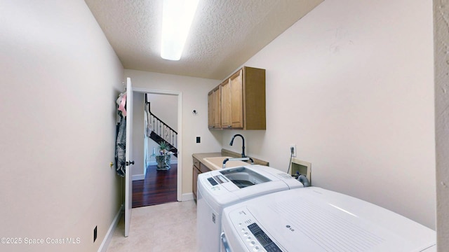 laundry room with a textured ceiling, cabinets, washer and dryer, and sink