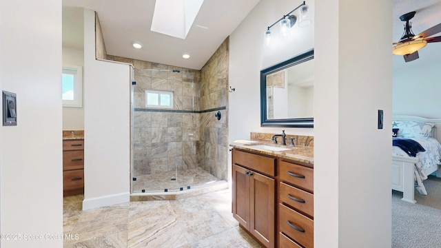 bathroom with ceiling fan, tiled shower, vanity, and a skylight