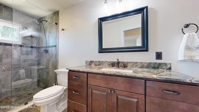 bathroom featuring toilet, vanity, and tiled shower