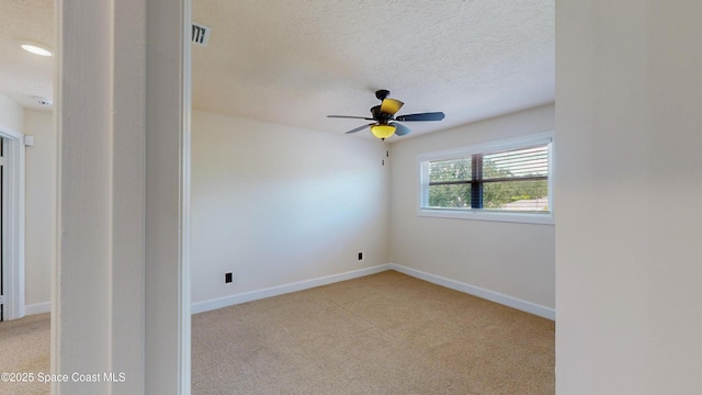 empty room featuring ceiling fan, light colored carpet, and a textured ceiling