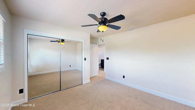 unfurnished bedroom featuring ceiling fan, light colored carpet, and a closet