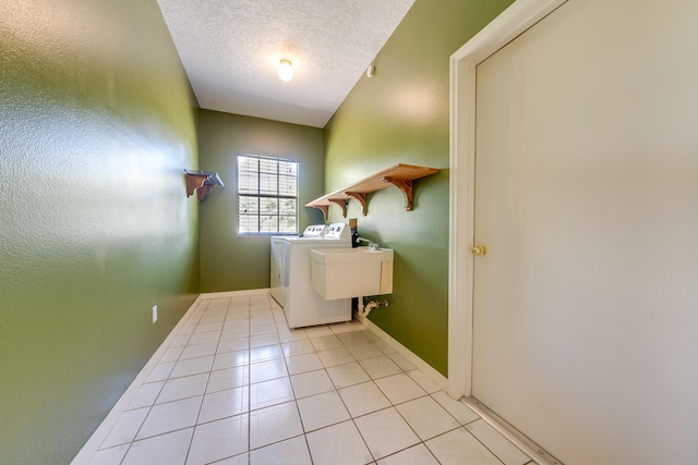 clothes washing area featuring a textured ceiling, light tile patterned floors, and washing machine and clothes dryer