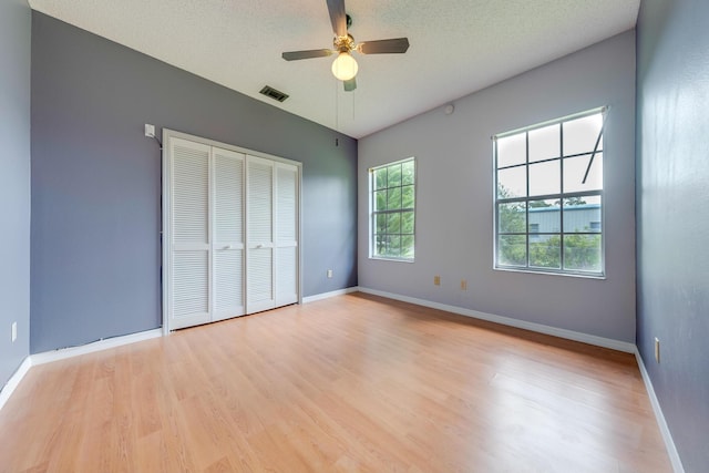 unfurnished bedroom with light wood-type flooring, ceiling fan, a closet, and a textured ceiling