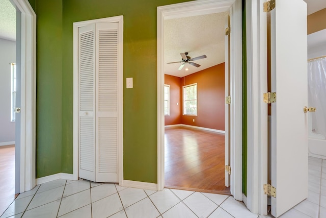 corridor with light tile patterned floors and a textured ceiling